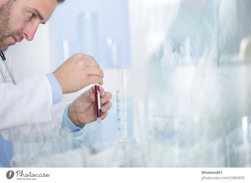 Mann untersucht Reagenzglas mit Flüssigkeit im Labor Test testen überprüfen ueberpruefen Laborant Laboranten arbeiten Arbeit Wissenschaft wissenschaftlich