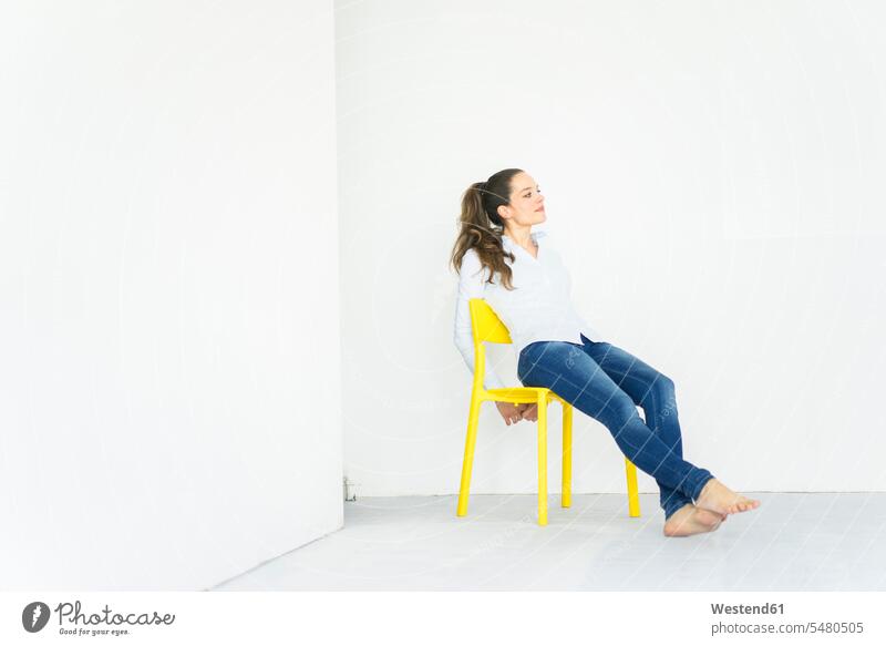 Frau sitzt auf einem gelben Stuhl sitzen sitzend Stuehle Stühle weiblich Frauen Erwachsener erwachsen Mensch Menschen Leute People Personen wegsehen
