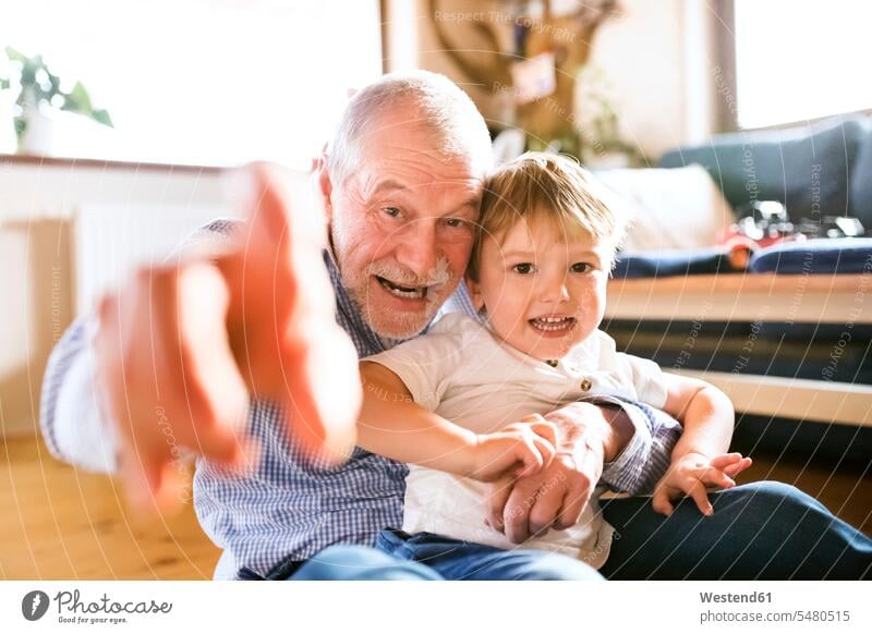 Grossvater und Enkel amüsieren sich zu Hause Gemeinsam Zusammen Miteinander spielen balgen sich balgen rangeln raufen herumtollen Enkelsöhne Enkelsohn Zuhause