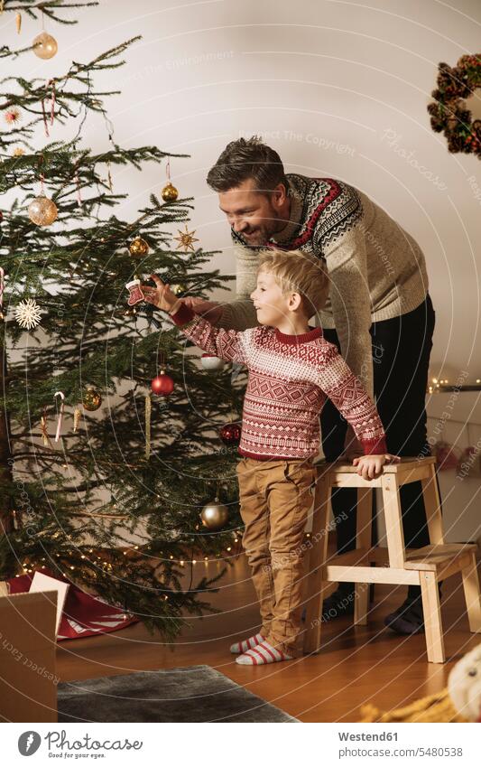 Vater und Sohn schmücken den Weihnachtsbaum Europäer Kaukasier Europäisch kaukasisch geschmueckt dekorieren dekoriert geschmückt schmuecken Kindheit