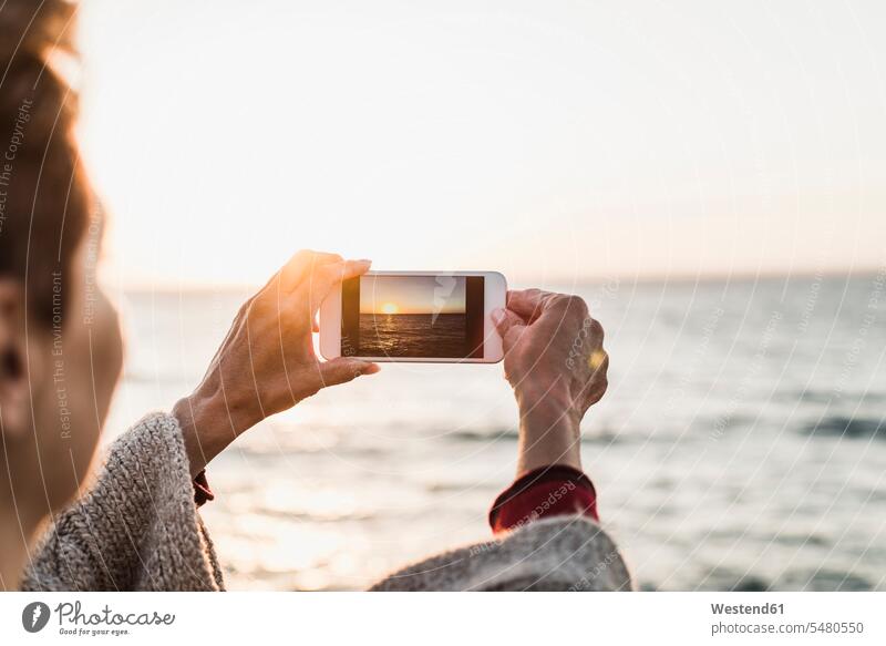 Frankreich, Halbinsel Crozon, Frau beim Fotografieren mit Smartphone Sonnenuntergang Sonnenuntergänge Urlaub Ferien Drahtlose Technologie drahtlose Verbindung
