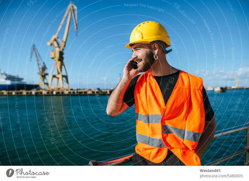 Lächelnder Hafenarbeiter beim Telefonieren lächeln telefonieren anrufen Anruf telephonieren arbeiten Arbeit Handy Mobiltelefon Handies Handys Mobiltelefone