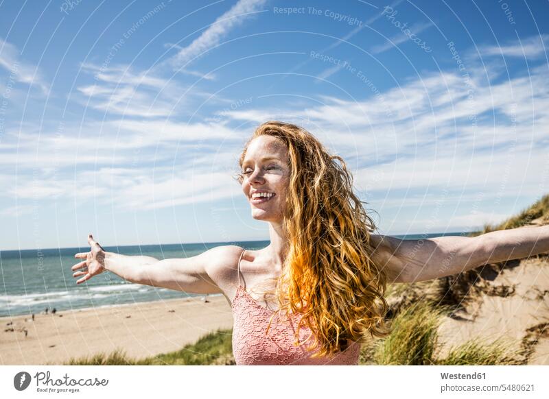 Niederlande, Zandvoort, glückliche Frau, die mit ausgestreckten Armen in den Dünen steht stehen stehend weiblich Frauen Strand Beach Straende Strände Beaches