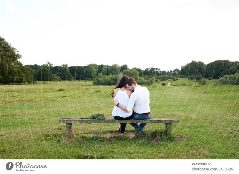 Rückenansicht eines auf einer Parkbank sitzenden Paares Natur Pärchen Partnerschaft Mensch Menschen Leute People Personen sitzt romantisch schwärmerisch