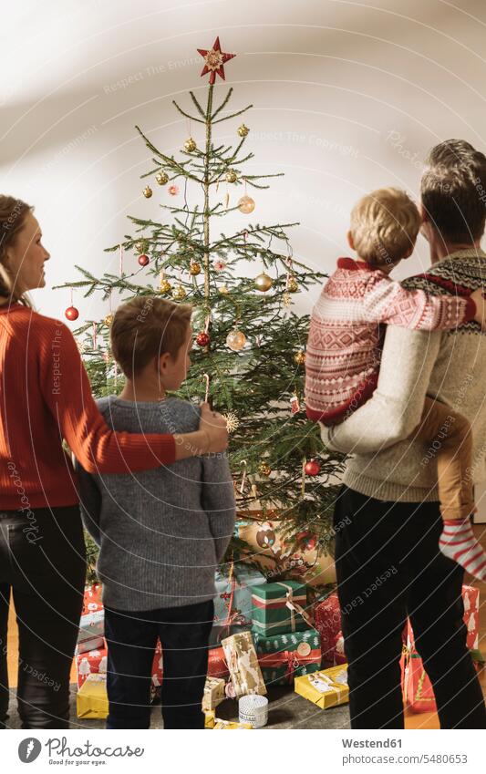 Glückliche Familie schaut auf den Weihnachtsbaum Europäer Kaukasier Europäisch kaukasisch Heiligabend 24.Dezember Heiliger Abend Kindheit Gemeinsamkeit zusammen