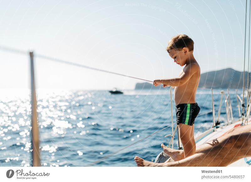 Kleiner Junge auf einem Segelboot stehen stehend steht Boot Boote Buben Knabe Jungen Knaben männlich Wasserfahrzeuge Kind Kinder Kids Mensch Menschen Leute