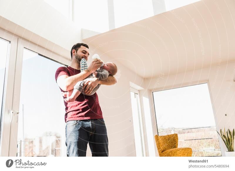 Vater füttert seinen kleinen Sohn mit der Flasche Zuhause zu Hause daheim Fläschchen geben Papas Väter Vati Vatis Papis Kind Babies Babys Kinder füttern Eltern