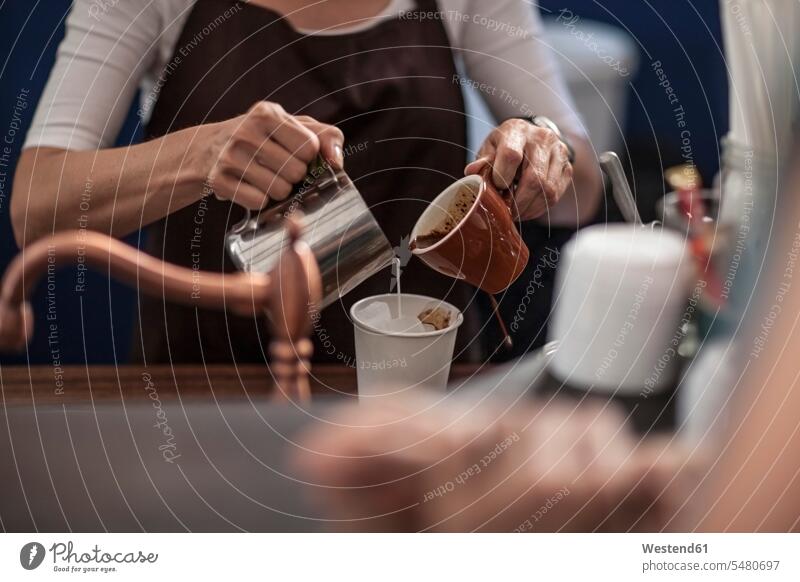 Barista bei der Zubereitung von Eiskaffee einschenken eingiessen gießen eingießen Tasse Tassen Cafe Kaffeehaus Bistro Cafes Café Cafés Kaffeehäuser Milch