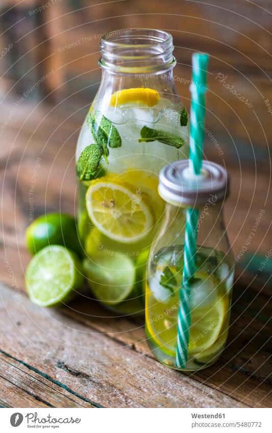 Glasflaschen mit Aufgusswasser mit Zitrone, Limette, Minzeblättern und Eiswürfeln Blatt Blaetter Blätter Limonen Limetten Limonelle Limonellen gesund
