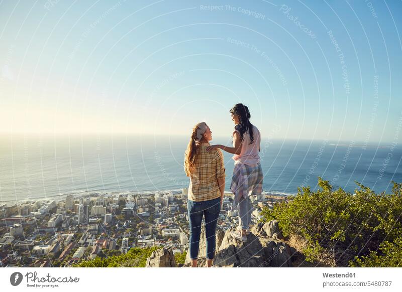 Südafrika, Kapstadt, Signal Hill, zwei junge Frauen mit Blick auf die Stadt und das Meer stehen stehend steht wandern Wanderung Aussicht Ausblick Ansicht
