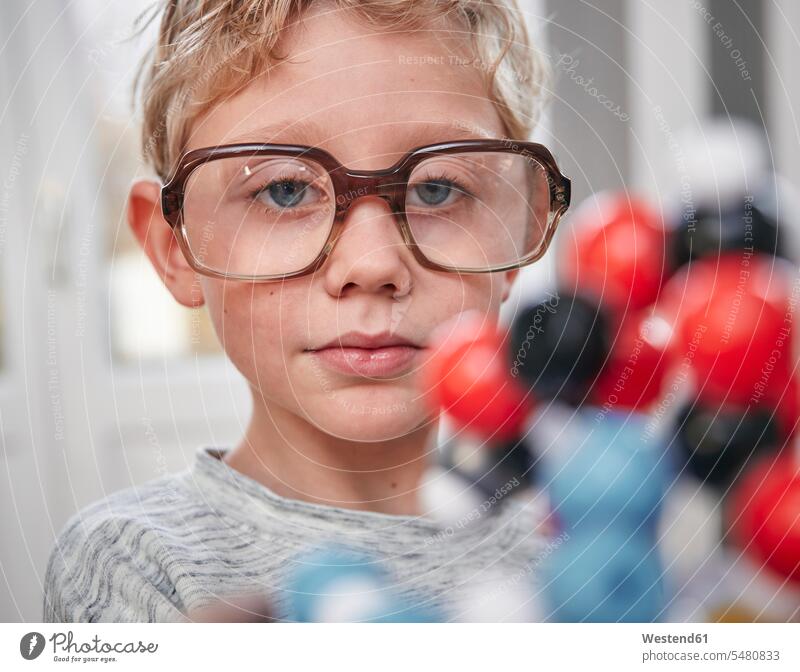 Junge mit übergroßer Brille beim Betrachten des Molekularmodells Modell Portrait Kind Mensch Europäer Neugier Chemie Early Learning Freizeitkleidung neugierig