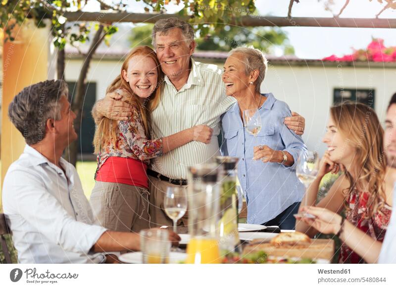 Glückliches älteres Ehepaar mit Familie beim gemeinsamen Mittagessen im Freien Familien glücklich glücklich sein glücklichsein Spaß Spass Späße spassig Spässe