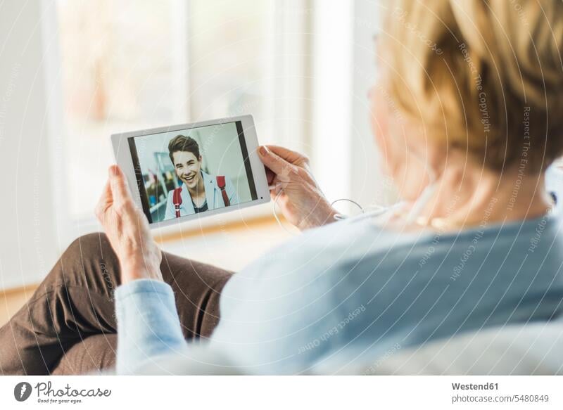 Ältere Frau betrachtet Bild eines jungen Mannes auf digitalem Tablet lächeln Komfort Annehmlichkeiten komfortabel Bequem Verbindung verbunden verbinden
