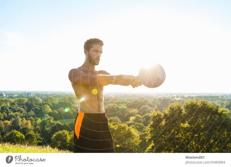 Mann übt mit Kettlebell im Freien Rundgewicht Kugelhantel Kettlebells Sportler Männer männlich trainieren Erwachsener erwachsen Mensch Menschen Leute People