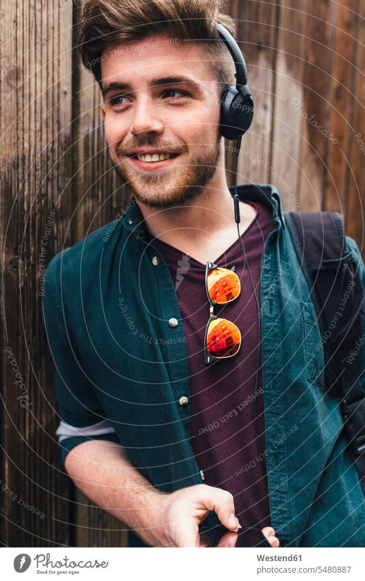 Porträt eines glücklichen jungen Mannes, der mit Kopfhörern Musik hört Männer männlich Kopfhoerer Erwachsener erwachsen Mensch Menschen Leute People Personen