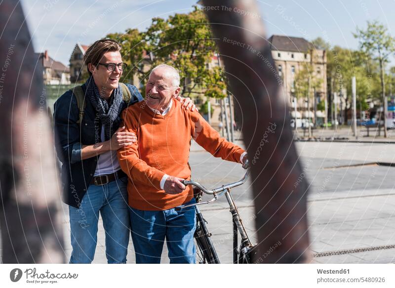 Glücklicher älterer Mann mit erwachsenem Enkel in der Stadt in Bewegung Spaß Spass Späße spassig Spässe spaßig lachen glücklich glücklich sein glücklichsein