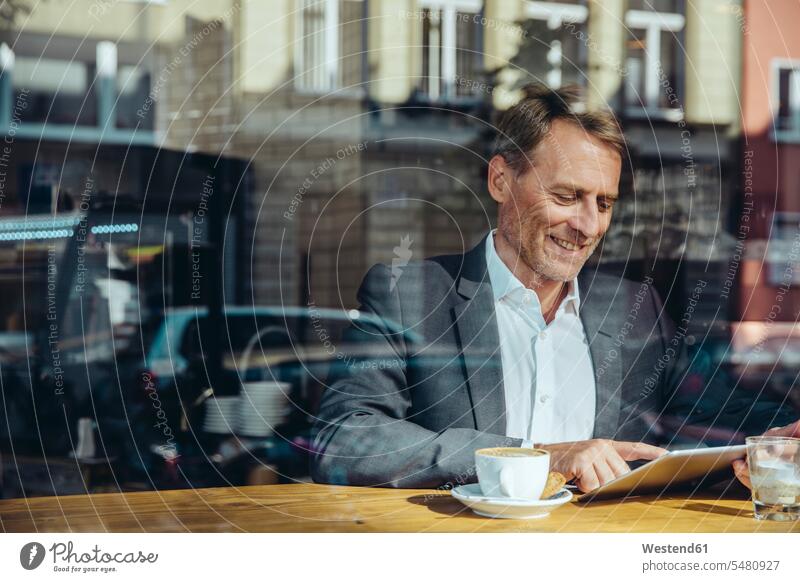 Geschäftsmann benutzt Tablette im Café Cafe Kaffeehaus Bistro Cafes Cafés Kaffeehäuser arbeiten Arbeit Businessmann Businessmänner Geschäftsmänner lächeln