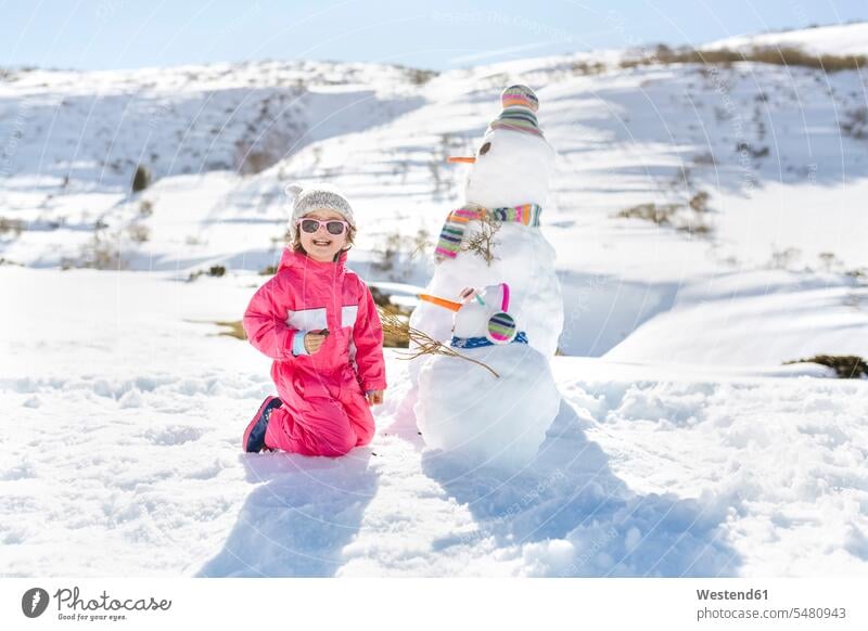 Mädchen spielt im Winter mit Schneemännern spielen Ferien Kindheit Freizeit Muße lächeln Schneemann Vergnügen genießen freuen Amüsement Freude vergnügt