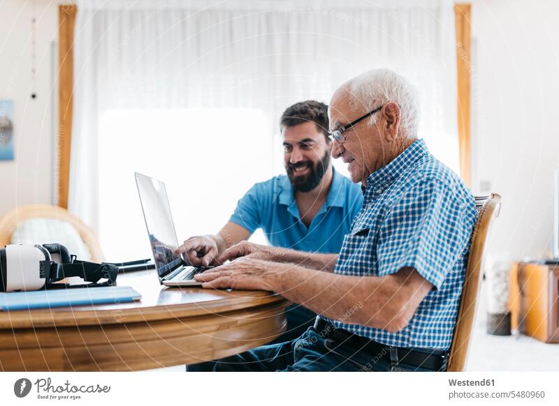 Erwachsener Enkel bringt seinem Großvater den Umgang mit dem Laptop bei Opa Großpapa Großpapas Opas Opi Großväter Opis Senior ältere Männer älterer Mann
