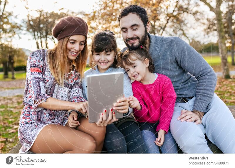 Familie sitzt auf einer Bank im herbstlichen Park und macht ein Selfie mit einem Tablet Familien Tablet Computer Tablet-PC Tablet PC iPad Tablet-Computer