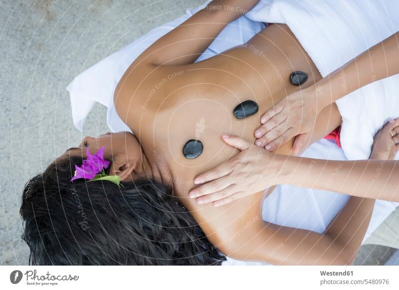 Junge Frau erhält eine Massage mit erhitzten Steinen auf dem Rücken Wellness Gesundheit weiblich Frauen Massagen massieren Erwachsener erwachsen Mensch Menschen