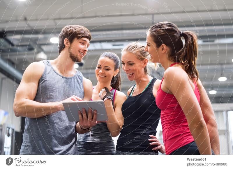 Gruppe glücklicher Sportler mit Tablette nach dem Training im Fitnessstudio ansehen lächeln trainieren Tablet Computer Tablet-PC Tablet PC iPad Tablet-Computer