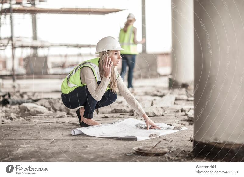 Frau in Arbeitsschutzkleidung am Mobiltelefon auf einer Baustelle Europäer Kaukasier Europäisch kaukasisch Bauindustrie Bauindustrien Bauwirtschaft Helm Helme