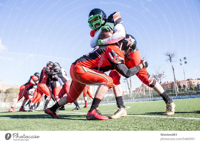 American-Football-Spieler wird während eines Spiels vom gegnerischen Spieler angegriffen American Football Match Helm Helme Sport Sportplatz Sportplaetze