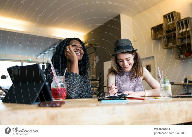 Zwei Freunde benutzen digitales Tablett im Café Brainstorming Ideenfindung Freundinnen Start-up Startups Start ups Start-ups Treffen Begegnung Gemeinsam