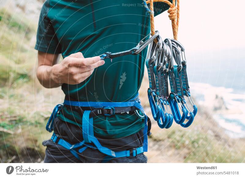 Junger Mann bereitet Kletterausrüstung vor Männer männlich Vorbereitung vorbereiten Seil Seile klettern steigen Karabinerhaken Haken Erwachsener erwachsen