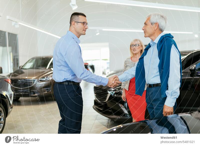 Älteres Ehepaar im Gespräch mit Verkäufer im Autohaus Paar Pärchen Paare Partnerschaft beraten beratend aussuchen auswählen Gemeinsam Zusammen Miteinander