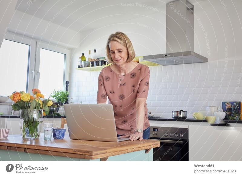 Reife Frau zu Hause mit Laptop in der Küche Notebook Laptops Notebooks weiblich Frauen Computer Rechner Erwachsener erwachsen Mensch Menschen Leute People