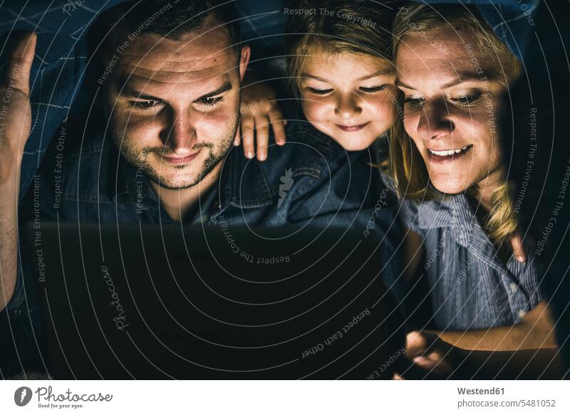 Glückliche Familie versteckt sich unter einer Decke und schaut sich einen Film auf einem Laptop an Decken Gemeinsamkeit zusammen gemeinsam WLan Wireless Lan