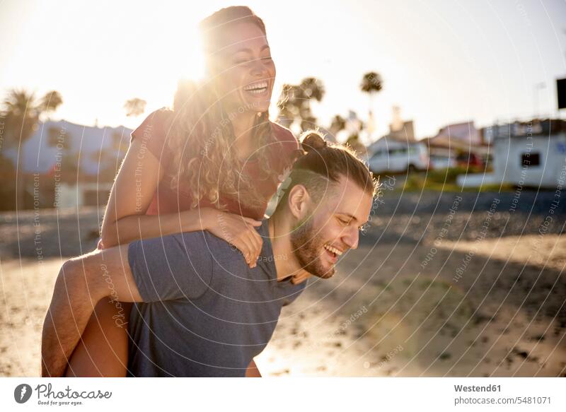 Junger Mann reitet seine Freundin am Strand Huckepack Paar Pärchen Paare Partnerschaft Beach Straende Strände Beaches glücklich Glück glücklich sein