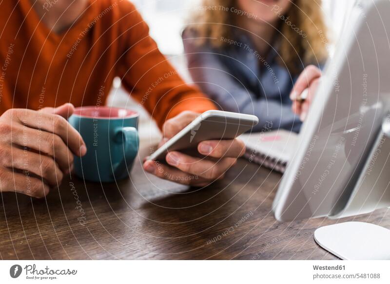 Zwei Kollegen am Schreibtisch mit Handy und digitalem Tablet Arbeitskollegen Mobiltelefon Handies Handys Mobiltelefone Telefon telefonieren Kommunikation