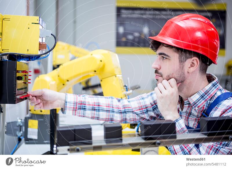 Mann mit Schutzhelm, der Industrieroboter einstellt arbeiten Arbeit einschalten anschalten Fabrik Fabriken Roboter industriell Gewerbe Industrien Technologie