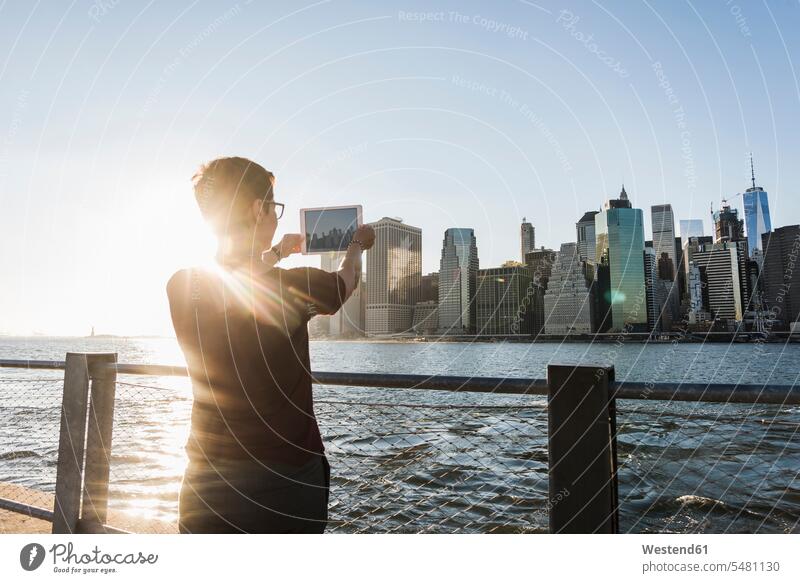 USA, Brooklyn, Rückenansicht einer Frau, die die Skyline von Manhattan mit einem Tablett fotografiert weiblich Frauen fotografieren Tablet Computer Tablet-PC