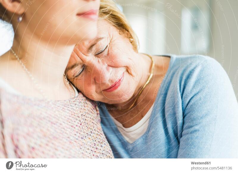 Ältere Frau mit geschlossenen Augen, die sich an die Schulter einer jungen Frau lehnt Europäer Kaukasier Europäisch kaukasisch Innenaufnahme drinnen