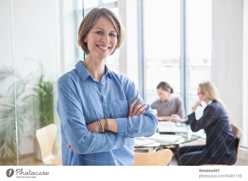 Porträt einer lächelnden Geschäftsfrau mit Kollegen im Hintergrund Europäer Kaukasier Europäisch kaukasisch Deutschland Innenaufnahme drinnen Innenaufnahmen