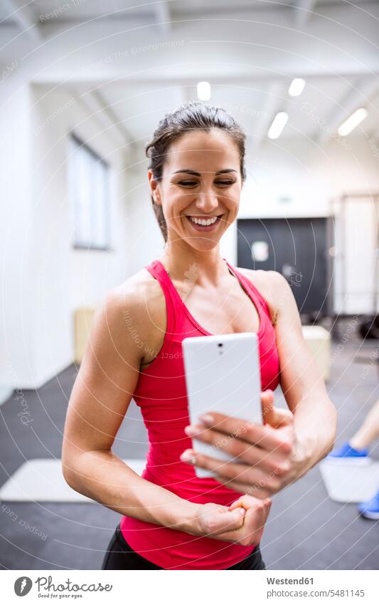 Junge weibliche Atheistin macht Selfies im Fitnessstudio Fitnessclubs Fitnessstudios Turnhalle Teilen Sharing fit Sportlerin Sportlerinnen Soziale Medien