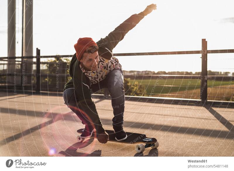 Junger Mann fährt Skateboard auf Parkebene Rollbretter Skateboards Skateboarden Skateboardfahren Skateboarding Männer männlich Freizeitsport Freizeitaktivität