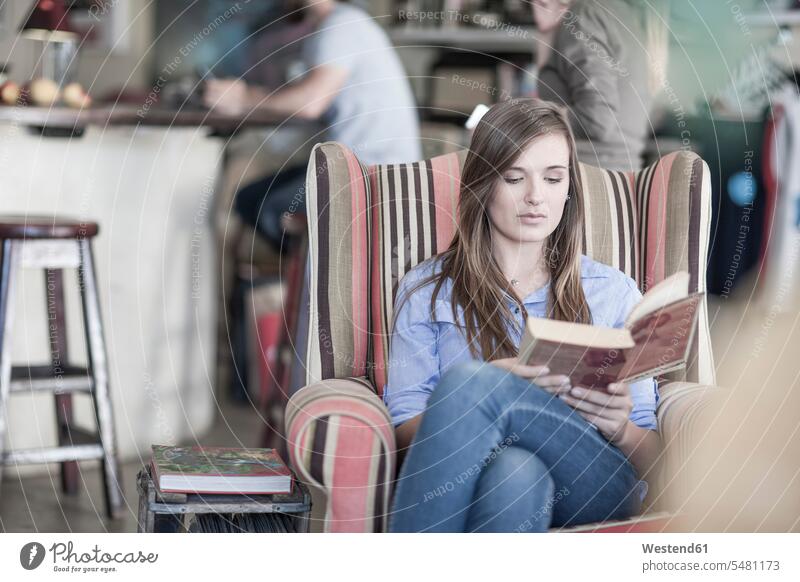 Junge Frau sitzt im Café und liest ein Buch Europäer Kaukasier Europäisch kaukasisch Dreiviertelansicht Sessel differenzierter Fokus Menschen zufällige Personen