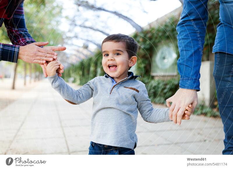 Porträt eines glücklichen Kleinkindes, das Hand in Hand mit seinen Eltern geht Europäer Kaukasier Europäisch kaukasisch beide Eltern beide Elternteile Portrait