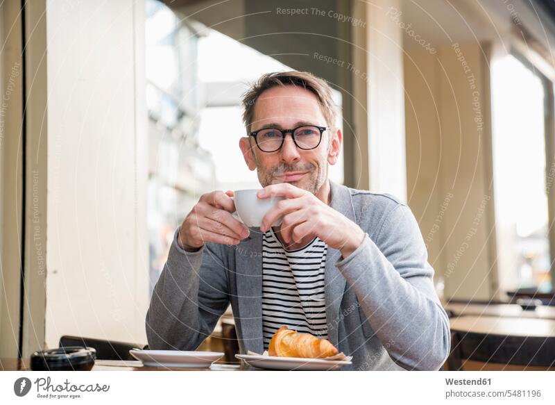 Porträt eines lächelnden reifen Mannes beim Kaffeetrinken in einem Straßencafé Männer männlich Straßencafe Straßencafes Strassencafe Strassencafes Erwachsener