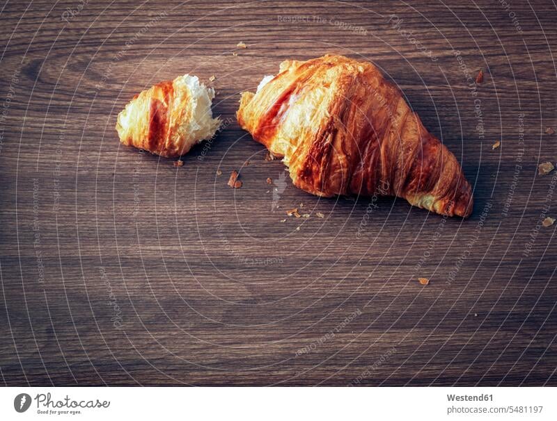 Croissant auf dunklem Holz Französisches Essen französisch Französische Küche Draufsicht Vogelperspektive von oben Aufsicht Niemand Textfreiraum hölzern Krümel