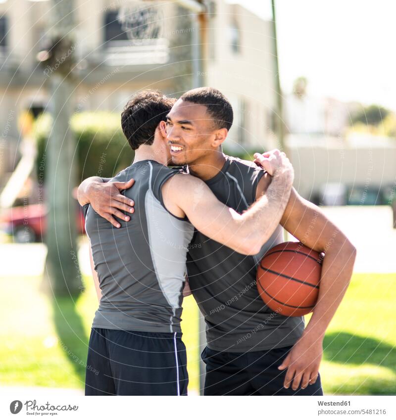 Zwei Basketballspieler umarmen sich im Freien Afroamerikanisch Afro-Amerikanisch Afroamerikaner Afro-Amerikaner fit multikulturell Tag am Tag Tageslichtaufnahme