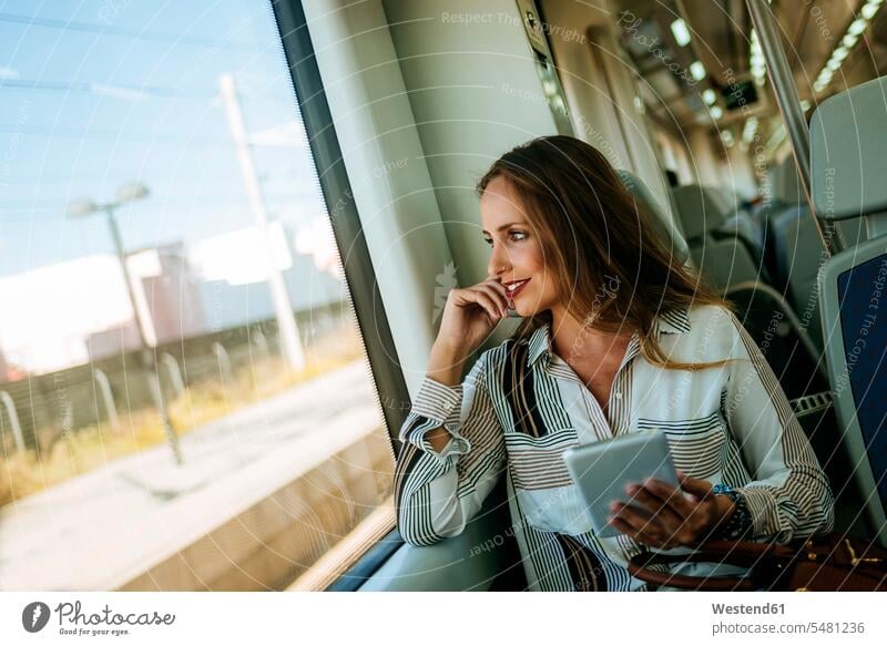 Lächelnde Frau im Zug mit einer Tablette weiblich Frauen Bahnen Züge lächeln Tablet Computer Tablet-PC Tablet PC iPad Tablet-Computer Erwachsener erwachsen