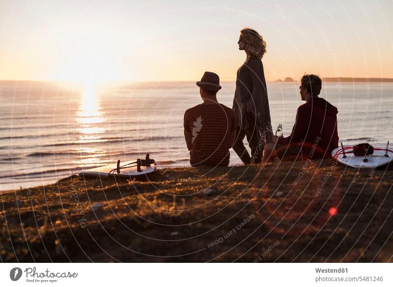 Drei Freunde genießen den Sonnenuntergang am Strand Freundschaft Kameradschaft Surfbrett Surfbretter surfboard surfboards Sonnenuntergänge geniessen Genuss Meer