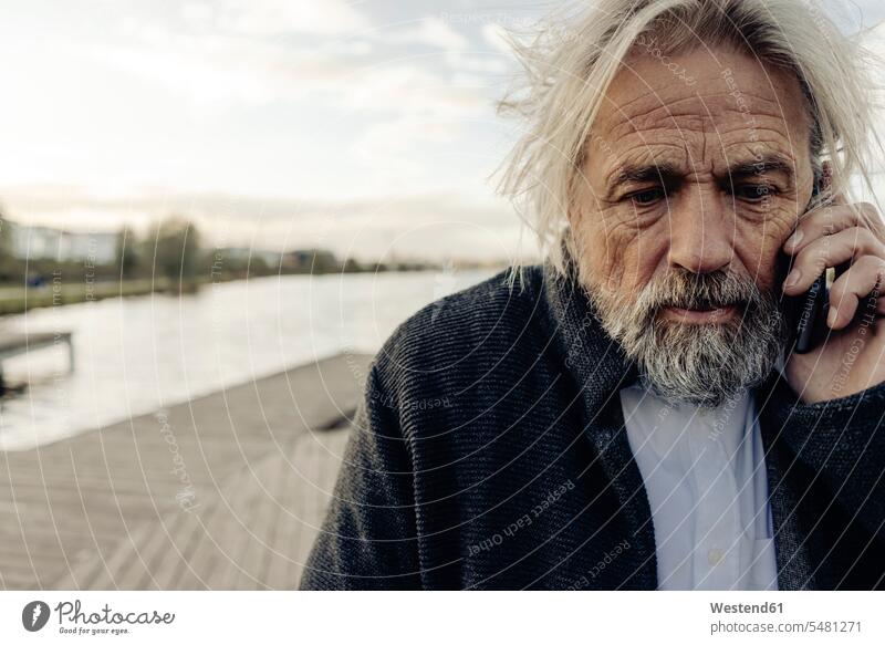 Porträt eines seriösen älteren Mannes mit Mobiltelefon an einem See Portrait Porträts Portraits Männer männlich Seen Handy Handies Handys Mobiltelefone