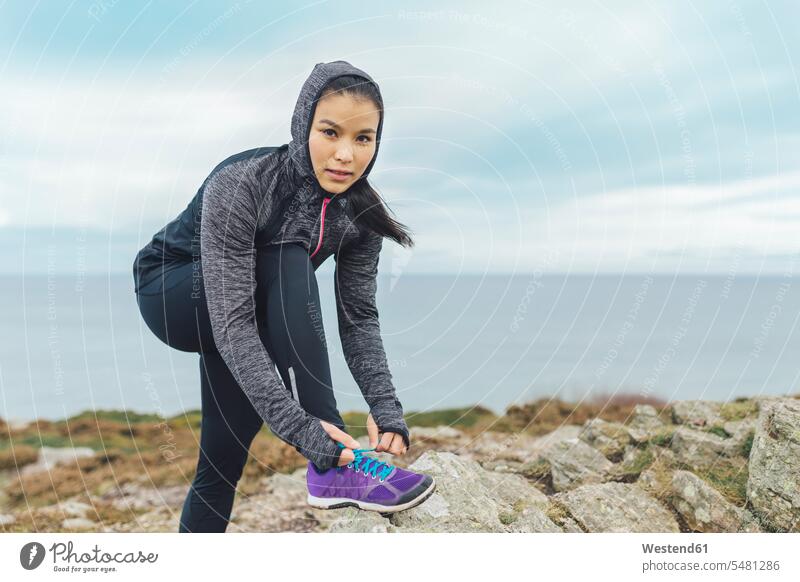 Irland, Howth, Frau schnürt ihre Schuhe an der Steilküste weiblich Frauen Küste Kueste Kuesten Küsten Erwachsener erwachsen Mensch Menschen Leute People